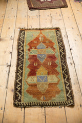 Hand-knotted texture and zigzag border of the distressed Oushak rug in copper orange and pale green.