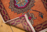 Distressed Oushak rug corner showing original selvage, worn pile, and vibrant hot pink accents.