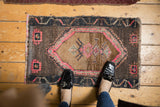 Distressed Oushak rug with faded diamond medallion, hot pink highlights, and textural wear.