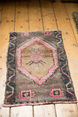 Distressed vintage Turkish Oushak mat corner, hot pink accents on a charcoal field.