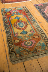 Hand-knotted distressed Oushak rug showing vibrant floral blossom, meandering vine border, and even wear.