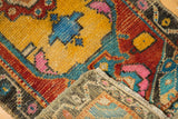 Textured pile of a distressed Oushak rug in gold, red, and pink, with its woven foundation revealed.