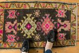 Vintage distressed Oushak rug mat with vibrant hot pink geometric motifs, shown styled.