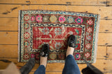 A vintage distressed Oushak rug mat with a red field, viewed from above to show scale.