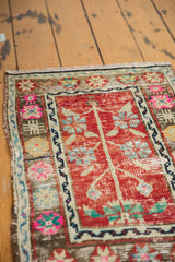 Angled view of the distressed Oushak's intact side selvage and colorful pomegranate motif border.