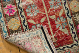 Folded corner of a distressed Oushak mat revealing the hand-knotted foundation and selvage.