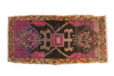Vintage Distressed Oushak rug with vibrant fuchsia and aubergine double diamond medallion on charcoal.