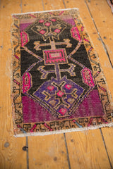 Distressed Oushak rug corner with vibrant fuchsia, aubergine, and charcoal geometric patterns.