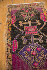 Distressed Oushak rug detail: fuchsia, aubergine, charcoal geometric plant motifs and selvage.