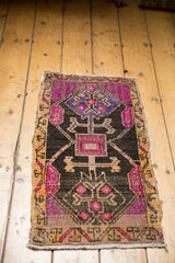 Oushak rug corner with fuchsia plant motifs, distressed pile, and saffron border.