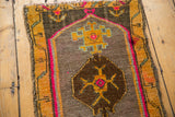 Distressed Oushak mat's dark brown diamond medallion, saffron yellow motifs, hot pink, and selvage.