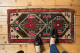 Distressed vintage Oushak rug corner showing hot pink and ivory motifs, with a madder root red-rust border.