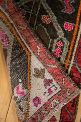 Folded distressed Oushak rug mat showing madder red border, hot pink, and chocolate brown motifs.