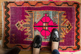 Vibrant hot pink medallion with serrated outer design on a distressed Oushak rug.