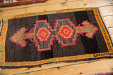 Vibrant pink and tangerine stepped medallions on a vintage distressed charcoal Oushak rug.