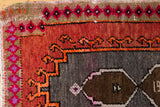 Geometric rust, dark grey, and hot pink patterns on a distressed vintage Oushak rug.
