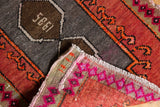 Distressed Oushak rug detail: 1985 date, rust field, and hot pink edge motifs.