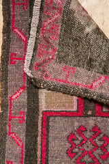 Folded corner of distressed Oushak rug showing rich red motif and hand-knotted reverse.