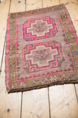 Distressed Oushak rug corner, revealing hot pink hooked rams horn motifs and original selvage.