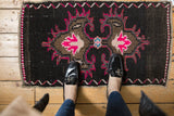 Distressed vintage Oushak rug with bright pink trefoil finials and floral medallion detail.