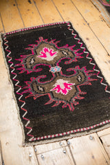 Distressed Turkish Oushak rug corner: vibrant hot pink zigzag border, chocolate brown field, soft wear.