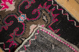 Distressed vintage Oushak rug showing bright pink and blue motifs, even pile wear, and intact selvage.