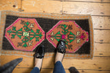 Distressed vintage Oushak rug hexagonal medallion with orange, hot pink, and green floral bursts.