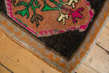 Corner of distressed Oushak rug, showing worn pile, vibrant floral motifs, and original selvage.