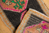 Folded vintage distressed Oushak rug, revealing original selvages and worn, colorful pile.