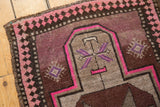 Distressed vintage Oushak rug corner with vibrant pink border and muted purple finned plants.