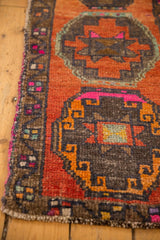 Distressed Oushak rug detail: abrashed orange field, bronze gul motif, and vibrant pink edge.