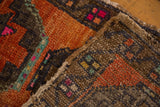 Folded distressed Oushak rug, showing low pile texture in burnt orange and dark bronze.