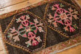 Geometric budded floral motif in pink, green, and saffron on the Oushak rug's charcoal field.