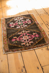 Distressed Oushak rug corner detail, low pile showing geometric pink, tangerine, green patterns.