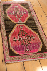 Distressed texture of a raspberry red primitive floral medallion on a vintage Oushak rug.