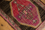 Primitive floral motifs on a distressed vintage Oushak rug in raspberry red and dark brown.