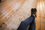 Faded ivory, pale charcoal, and cherry red distressed Turkish Oushak runner with multi-medallion pattern.