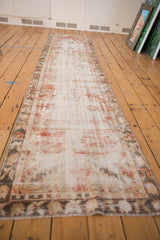 Distressed Oushak rug runner end, with faded cherry red, ivory border, and secure fringe.