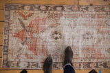 Distressed Oushak runner underfoot, showcasing faded ivory, cherry red, and charcoal hues.