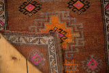 Distressed Oushak rug corner folded, revealing hand knotted pile and woven reverse.