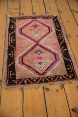 Distressed Oushak rug corner: charcoal border, pink geometric motifs, and even wear.