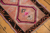 Geometric motifs and distressed texture on a vintage Oushak rug with pink and black borders.