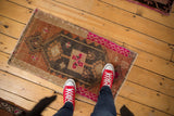 Corner detail of distressed Oushak mat, with vibrant fuchsia border and geometric motifs.