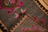 Distressed Oushak rug corner; bubble gum pink hook-and-latch motifs and textured pile.