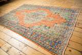 Distressed orange field and vibrant blue-green border of a vintage Oushak rug.