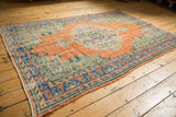 Decorative distressed Oushak rug with fully secured side and worn burnt orange field, blue border.