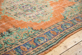 Distressed burnt orange Oushak rug showing mint green patterns, even wear, and patterned blue border.