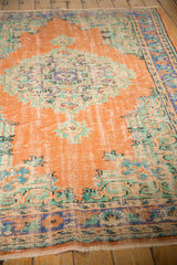Distressed vintage Oushak carpet pile texture, with burnt orange, mint green, and blue medallion details.