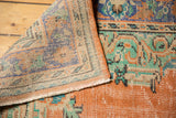Distressed vintage Oushak carpet corner, revealing worn burnt orange pile and hand-knotted foundation.