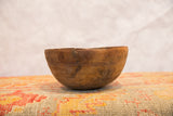 Primitive hand-carved African bowl, showing weathered wood, visible cracks, and etched patterns.